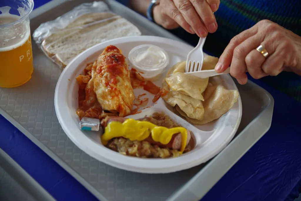 An ethnic platter on a tray: holubki, perohi, kielbasa with sauerkraut, and rye bread